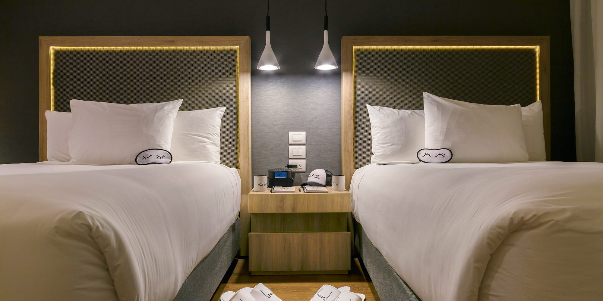 two beds with pillows and slippers on the floor