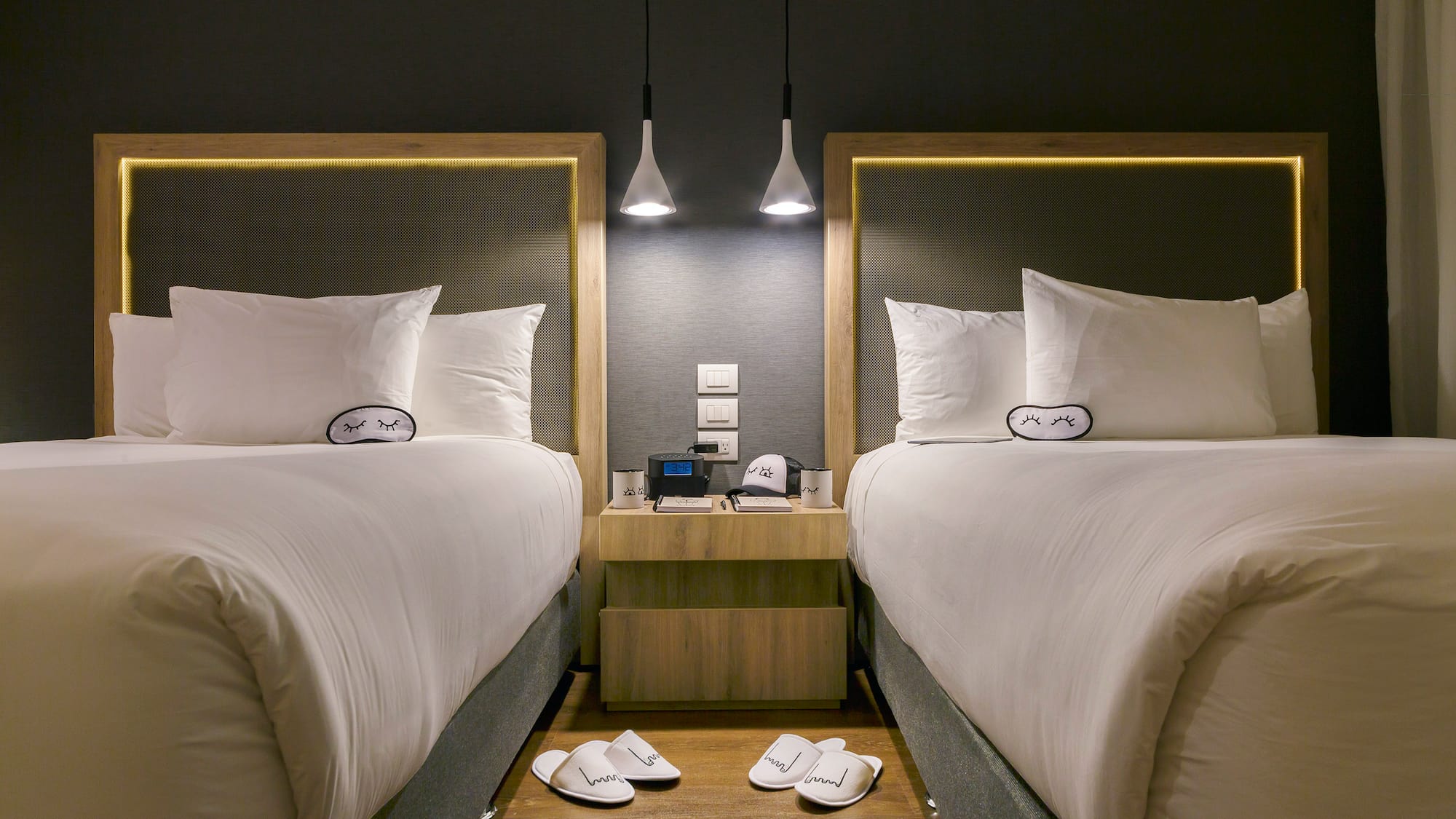 two beds with pillows and slippers on the floor