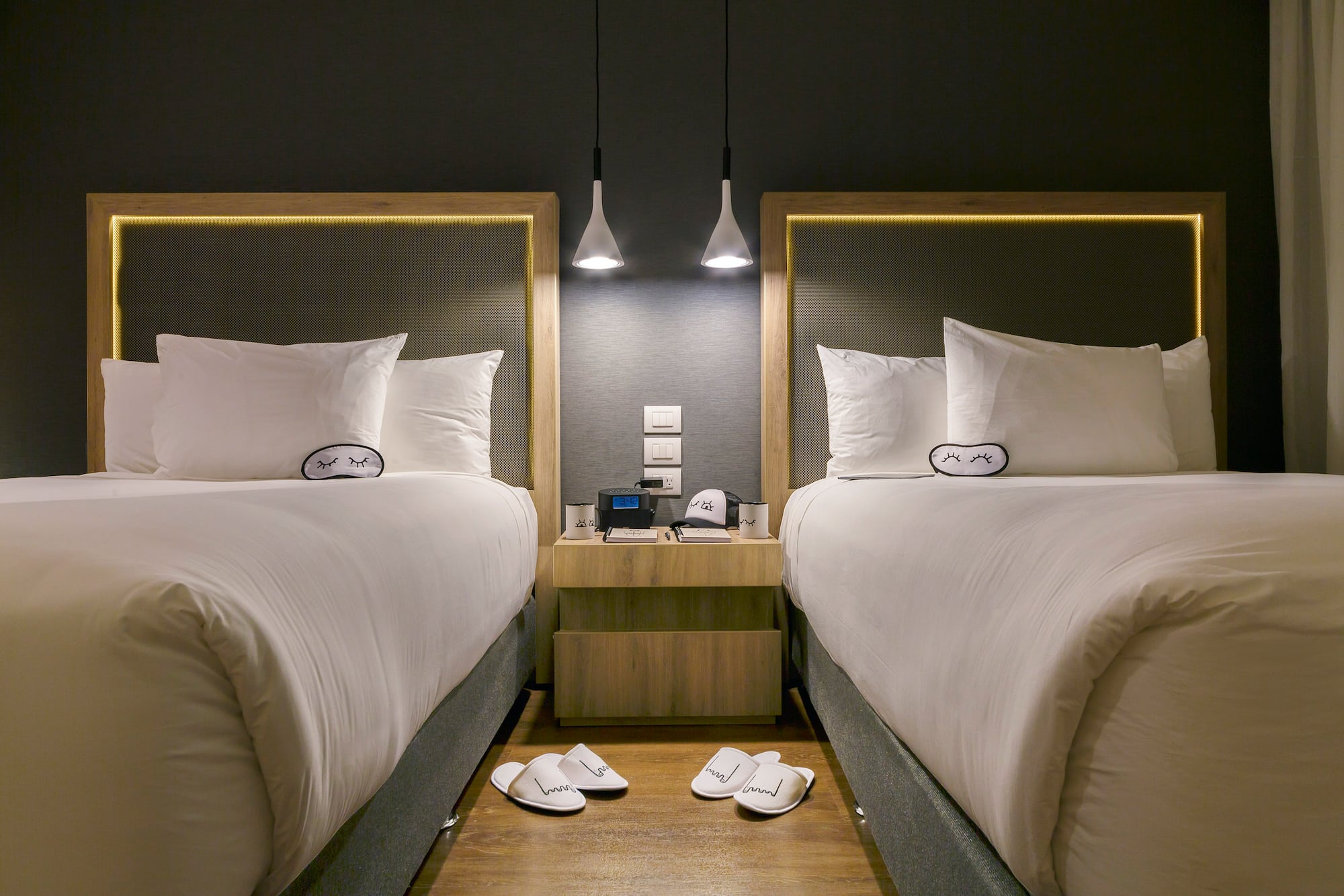 two beds with pillows and slippers on the floor