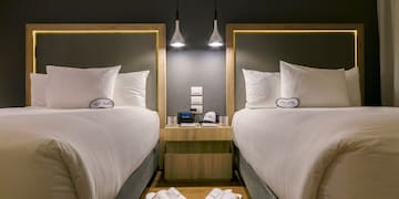 two beds with pillows and slippers on the floor