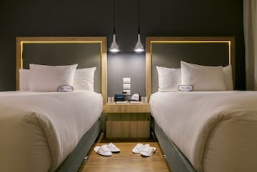 two beds with pillows and slippers on the floor