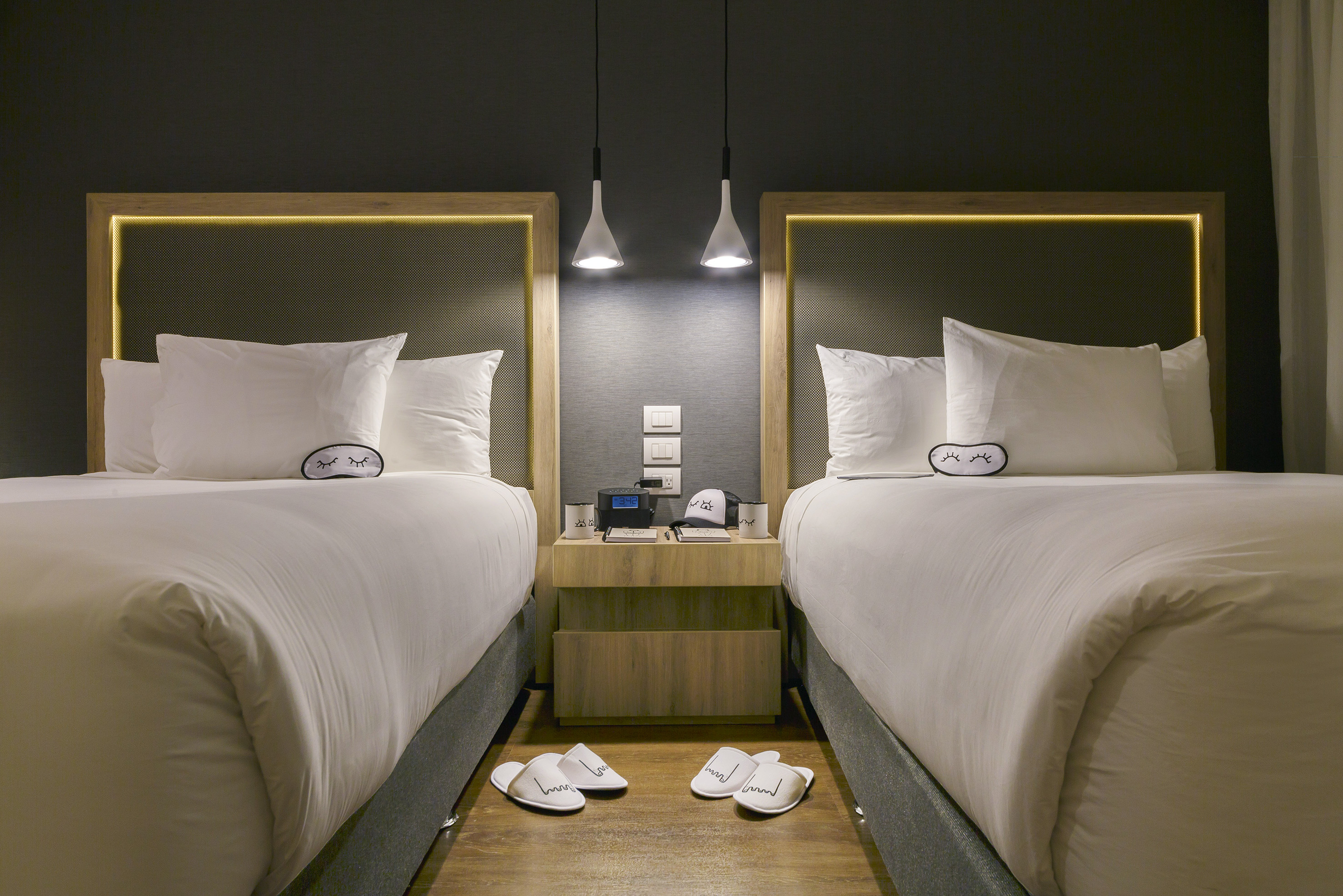 two beds with pillows and slippers on the floor