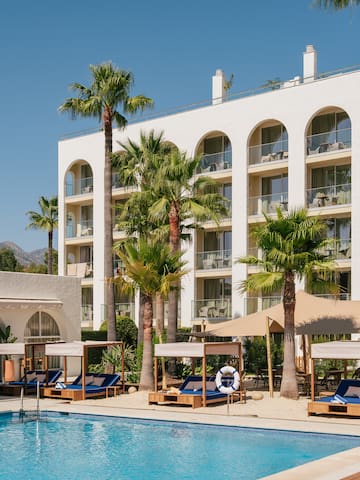 a pool with lounge chairs and palm trees in front of a hotel