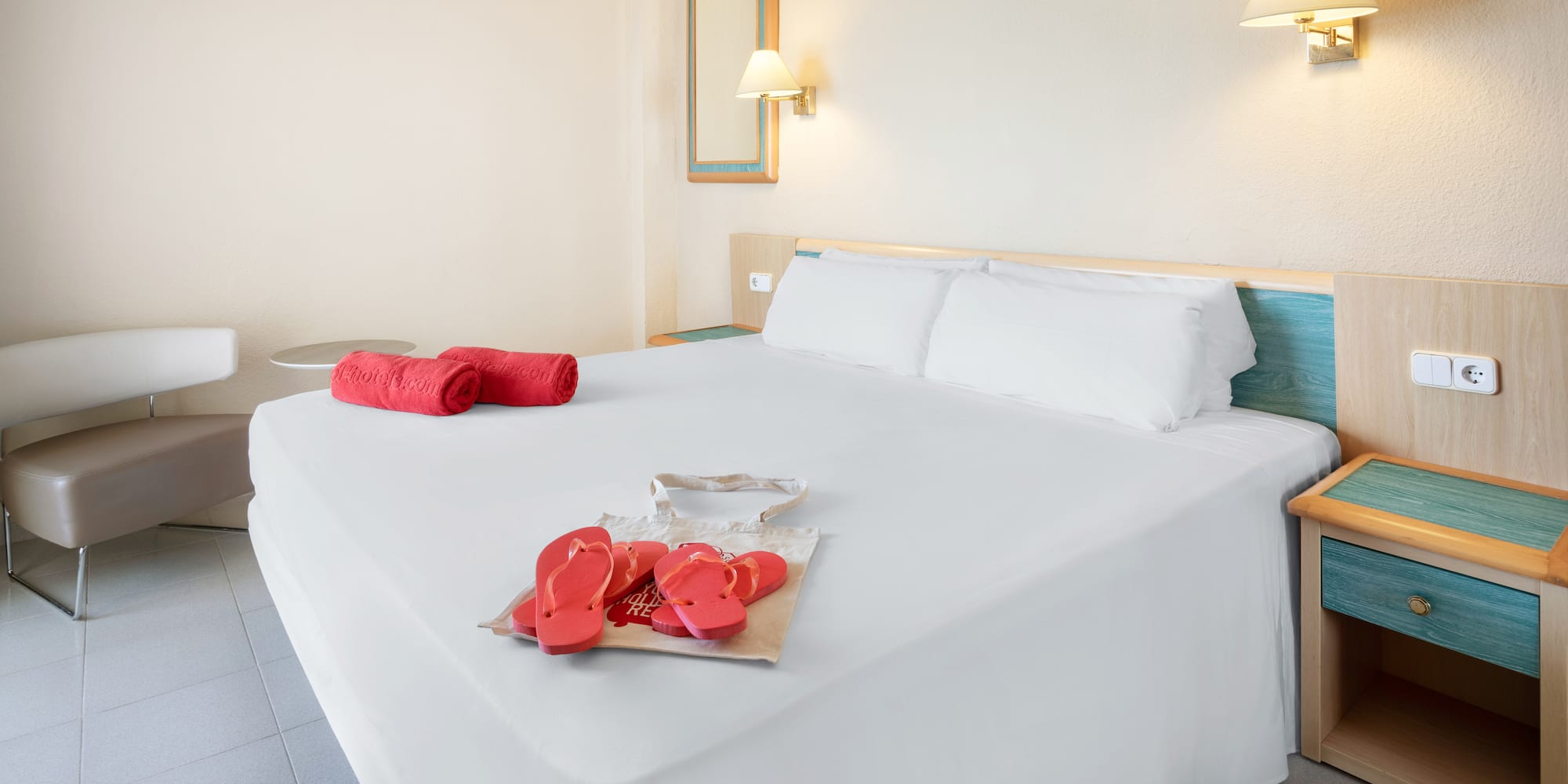 a bed with white sheets and red sandals on it