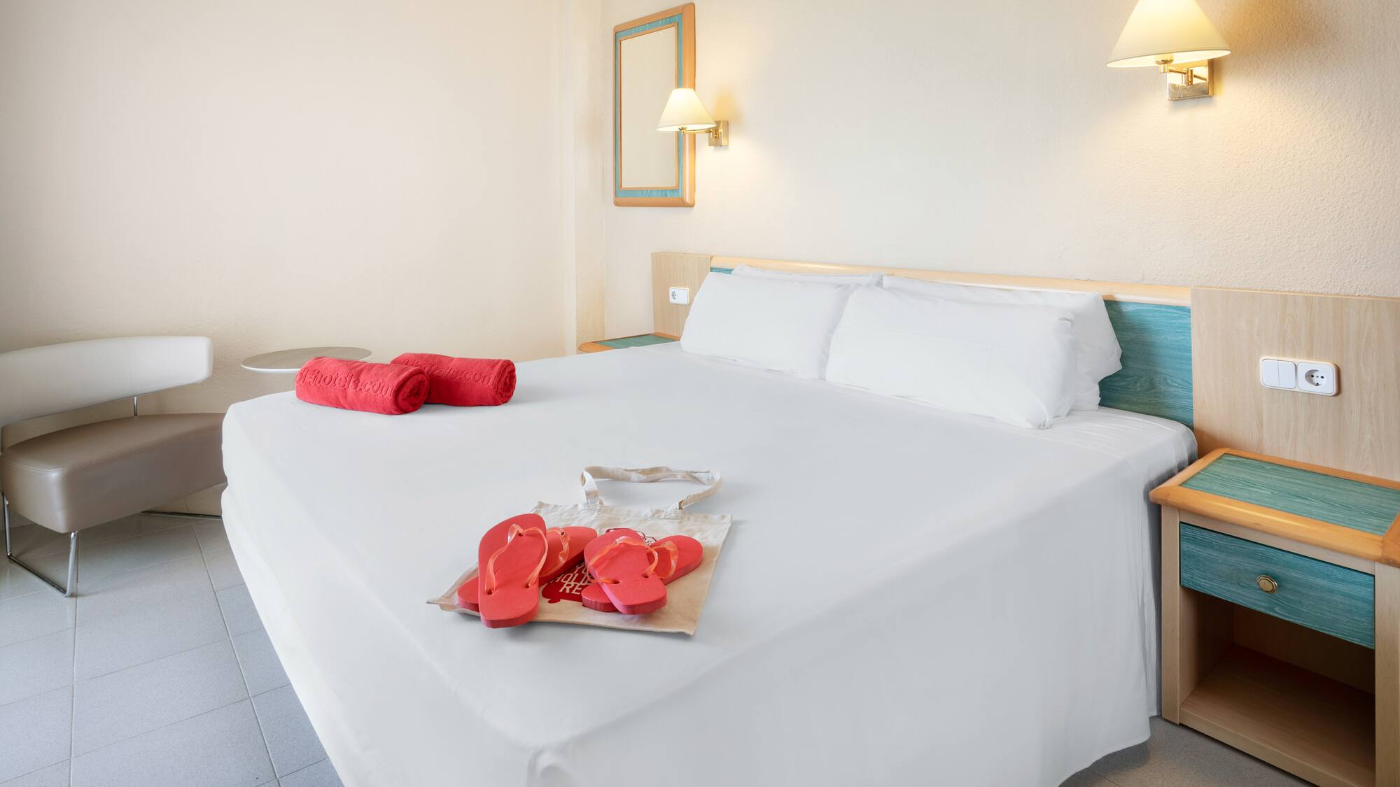 a bed with white sheets and red sandals on it