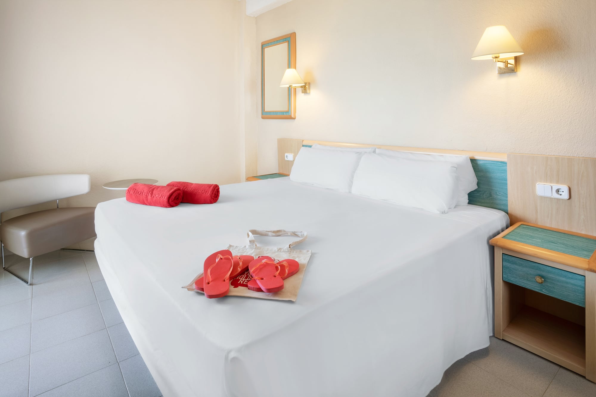 a bed with white sheets and red sandals on it