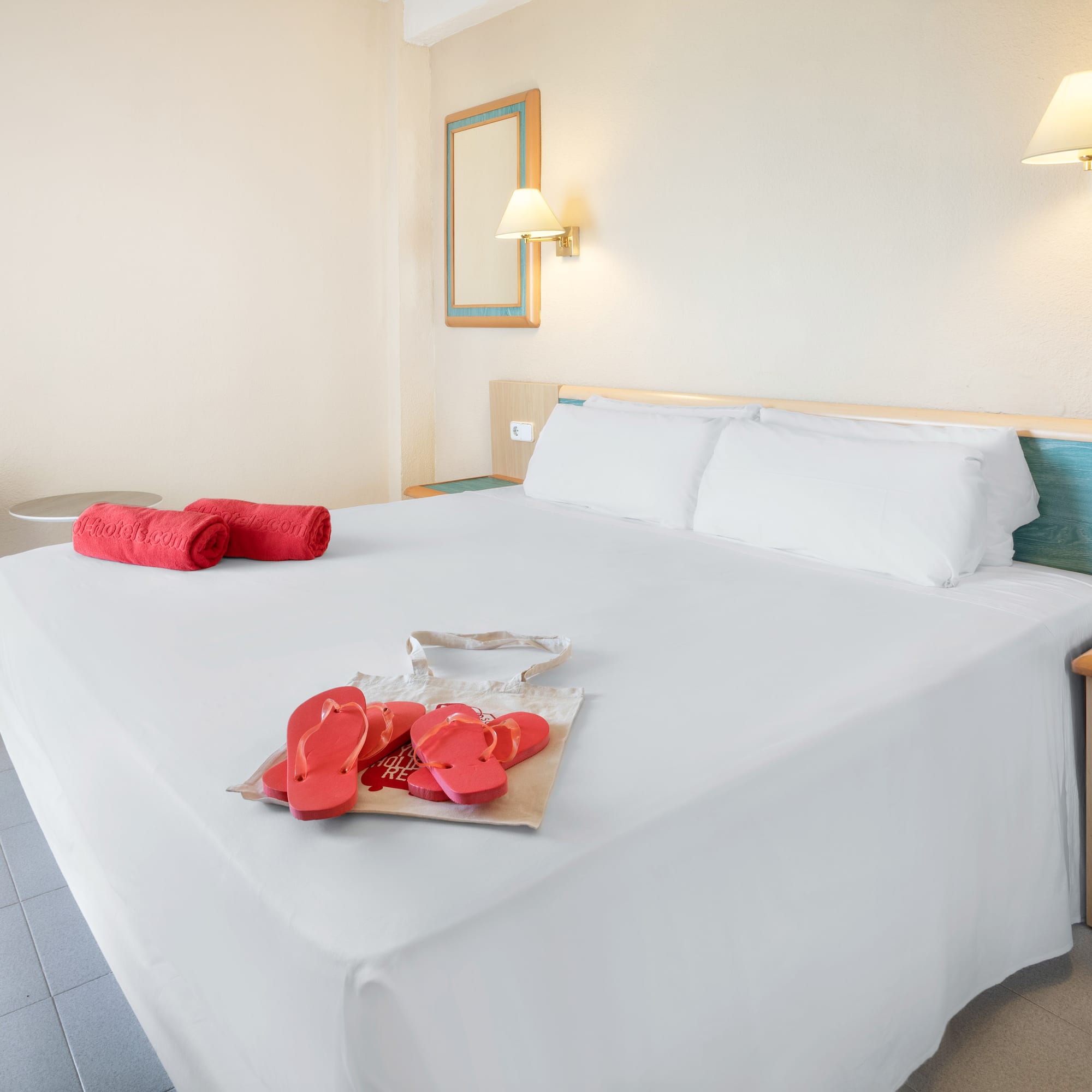 a bed with white sheets and red sandals on it