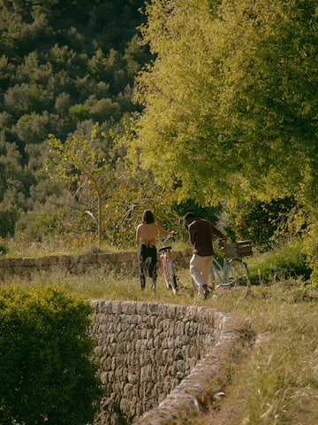 a man and woman walking by a stone wall with trees