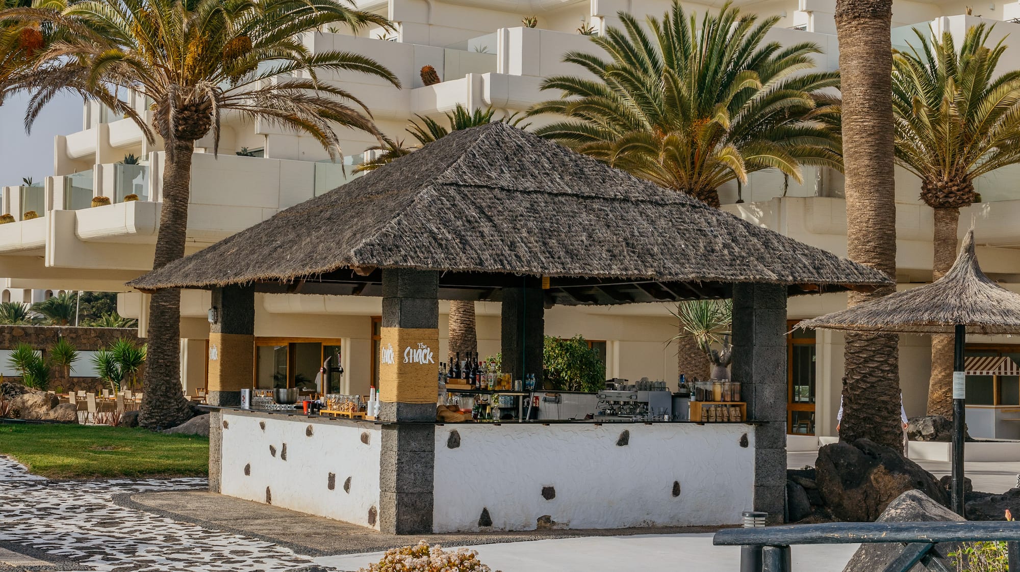 a bar with a straw roof and palm trees