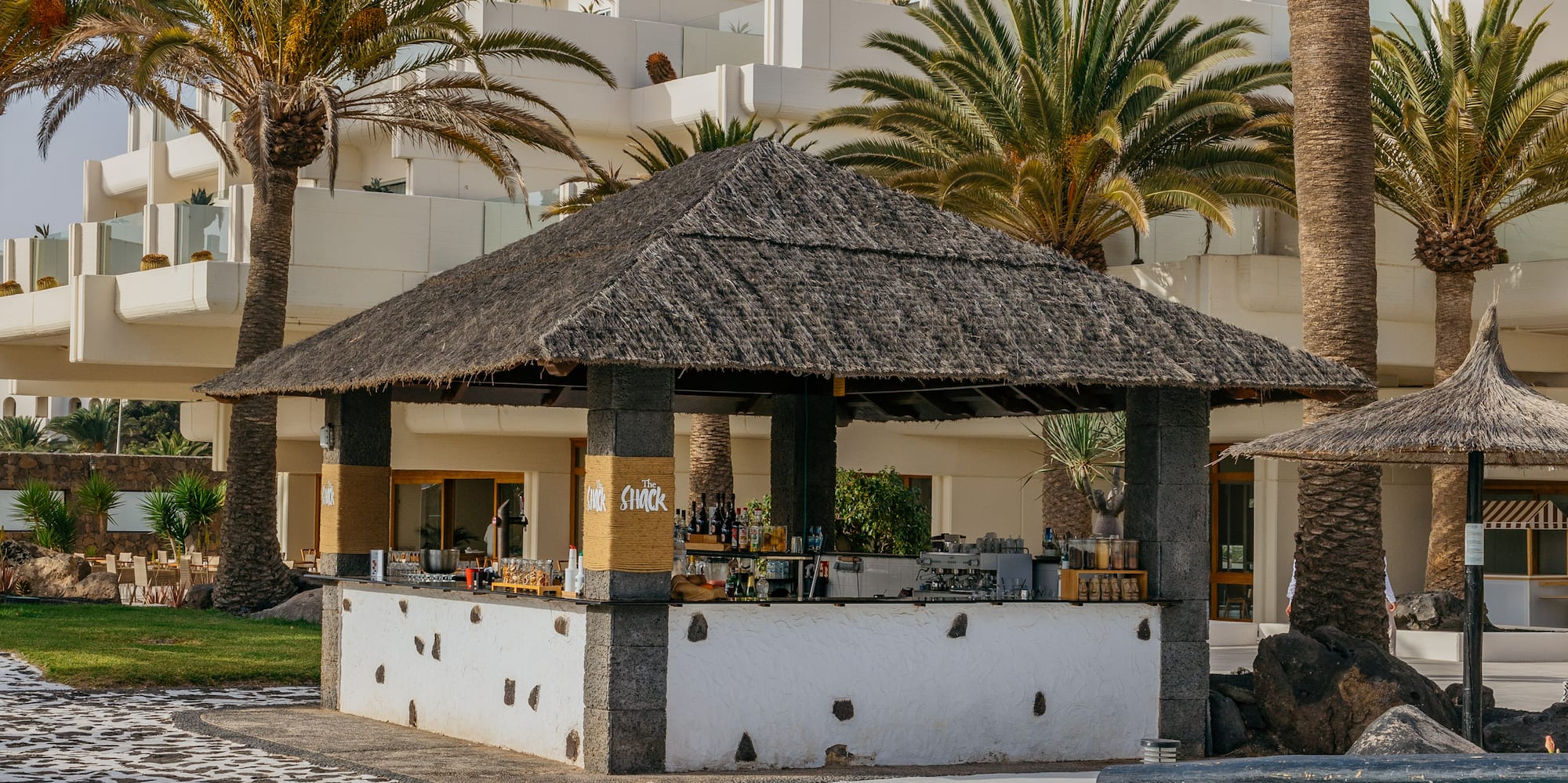 a bar with a straw roof and palm trees