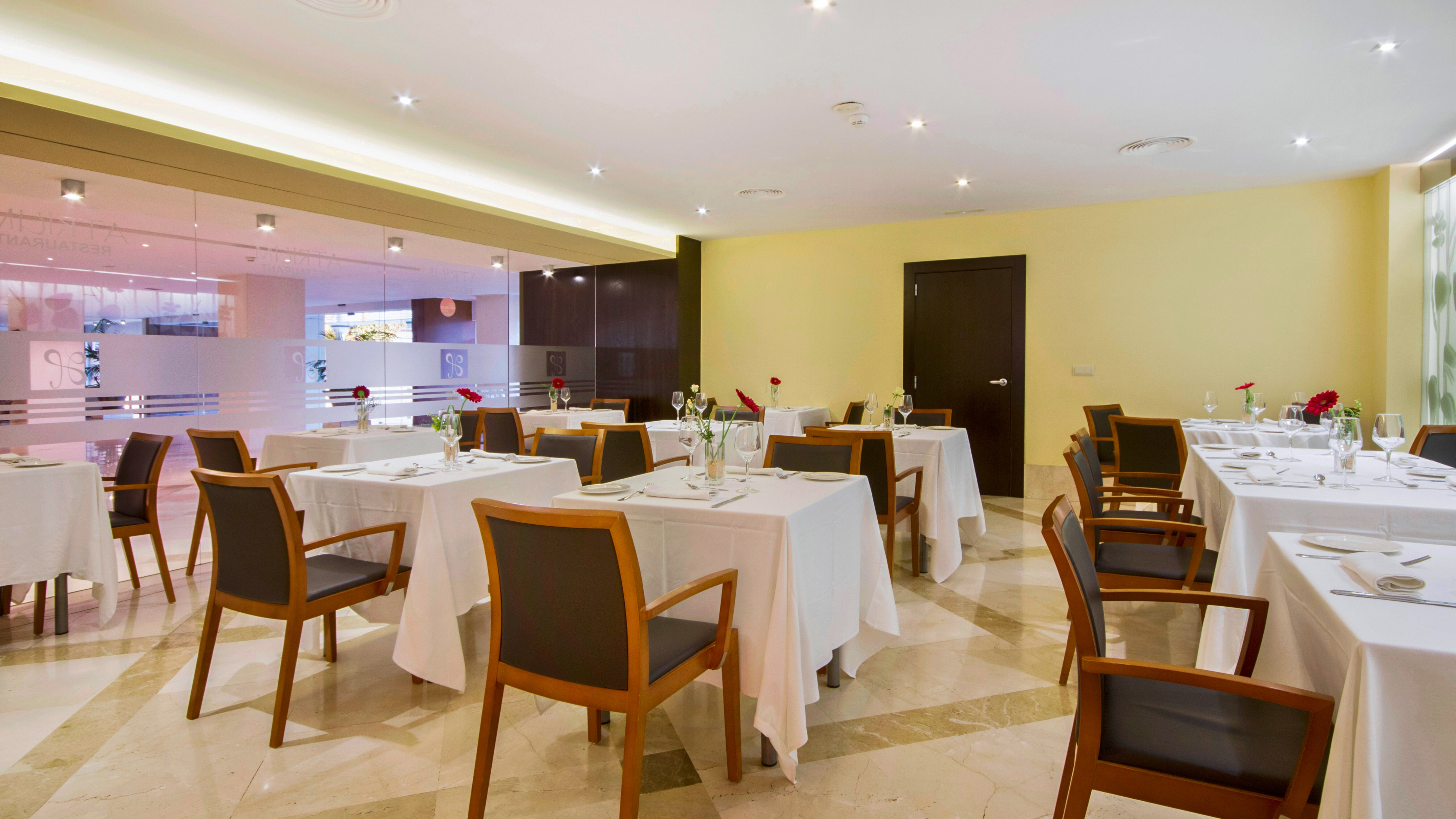 Elegant hotel restaurant dining area with multiple set tables and chairs.