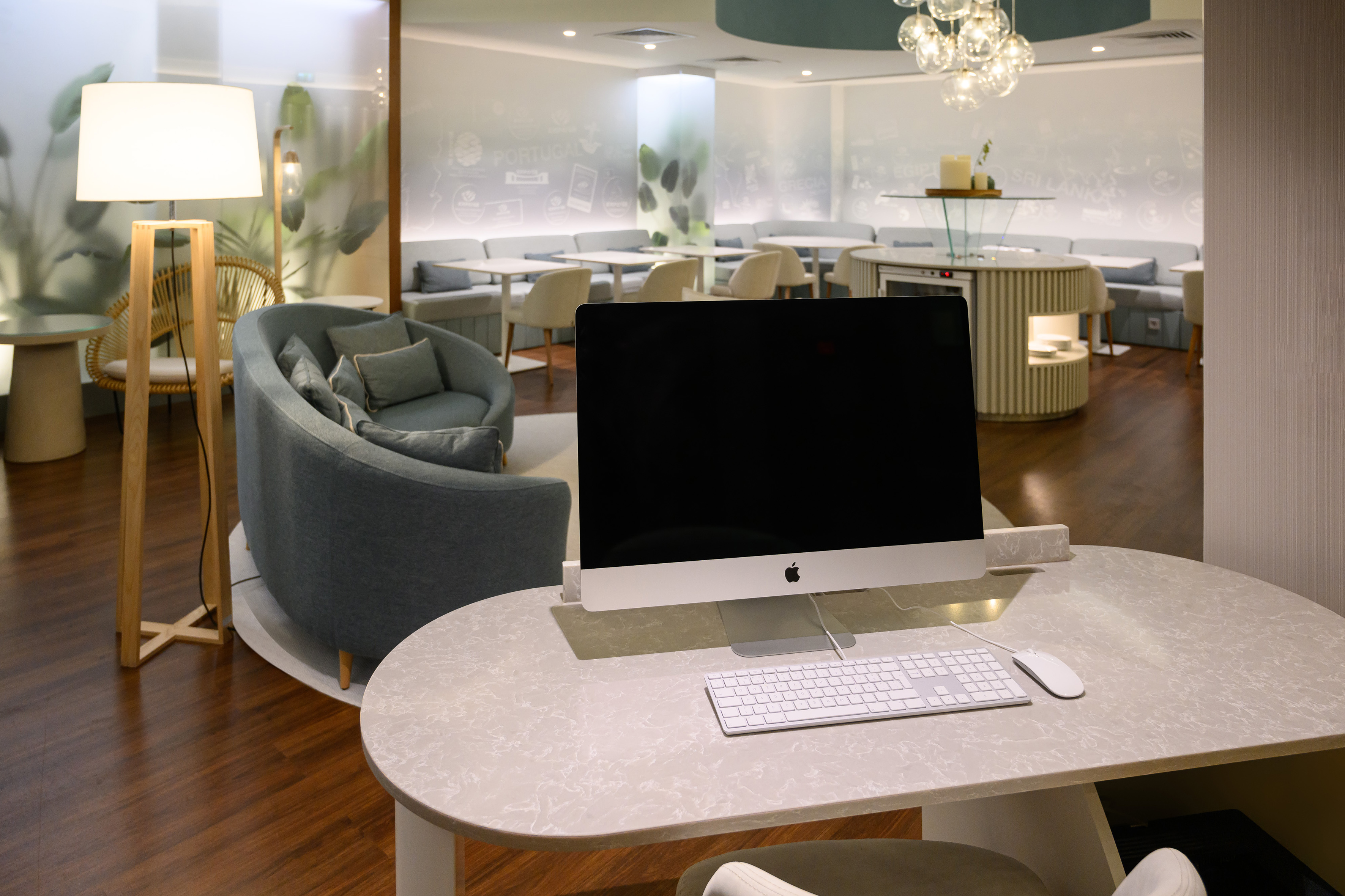 Modern lounge with iMac on desk, stylish sofa, and warm lighting.