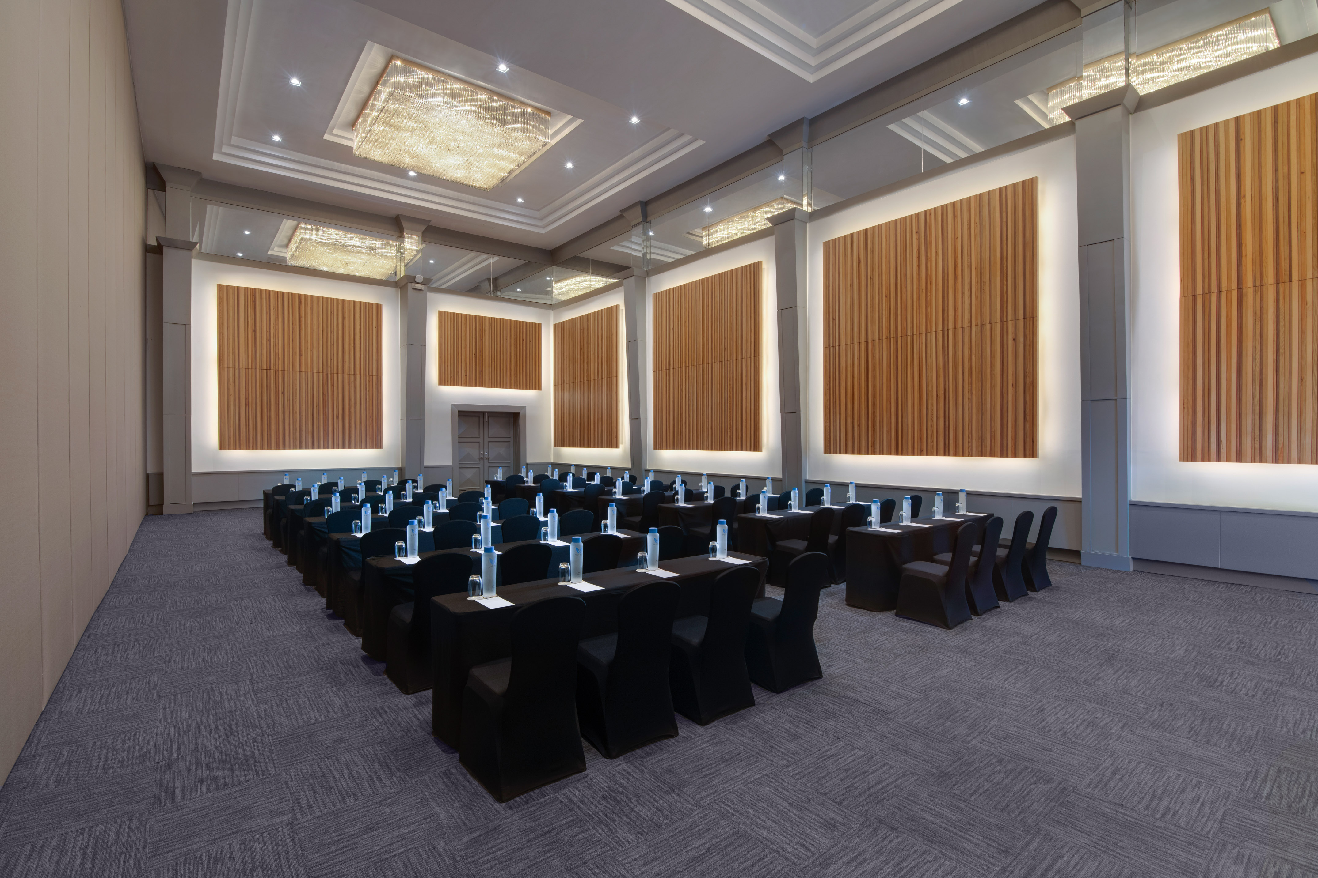 Elegant conference room with black tables, chairs, and illuminated wood panels.
