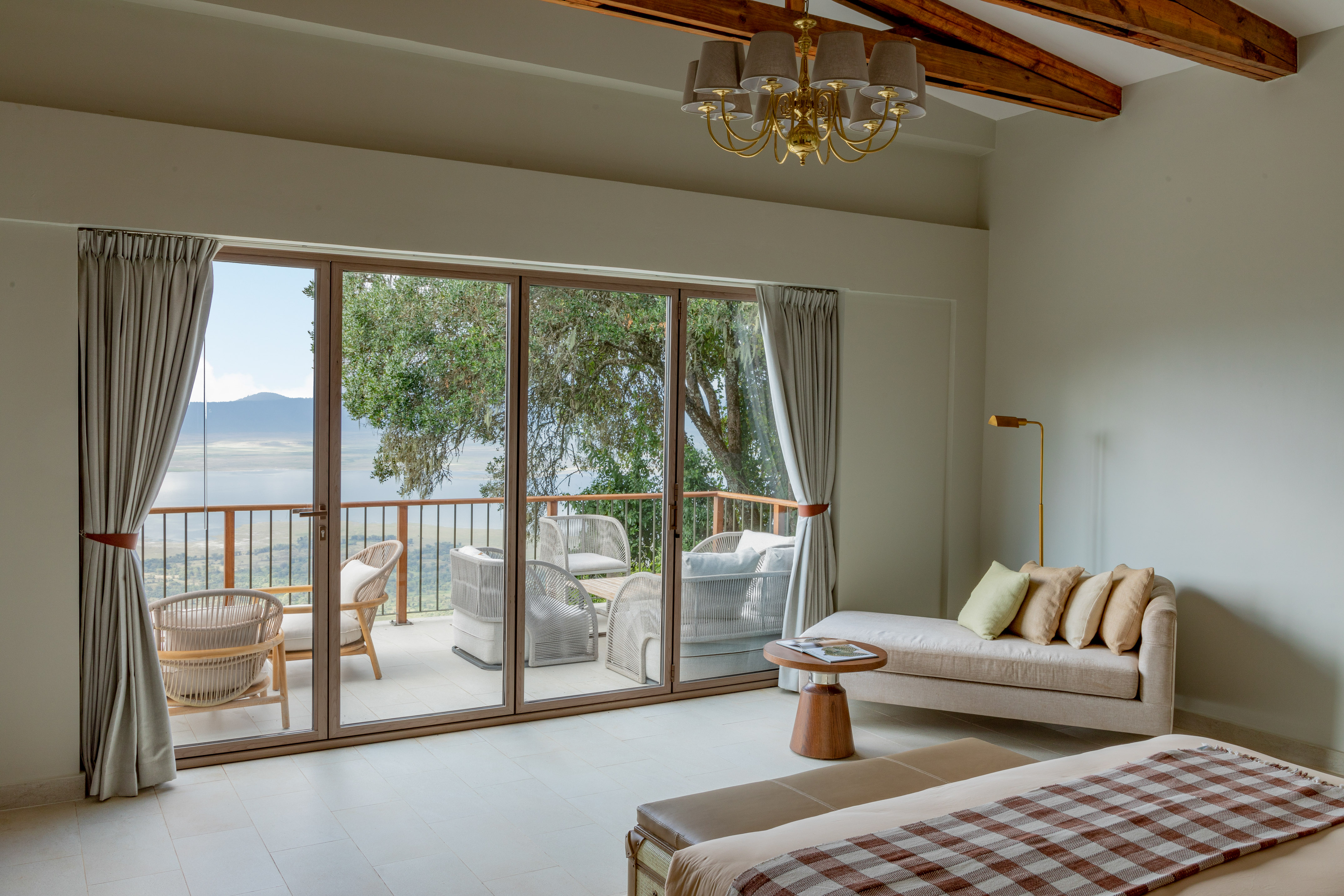 Luxury safari suite with balcony overlooking a vast crater lake landscape.