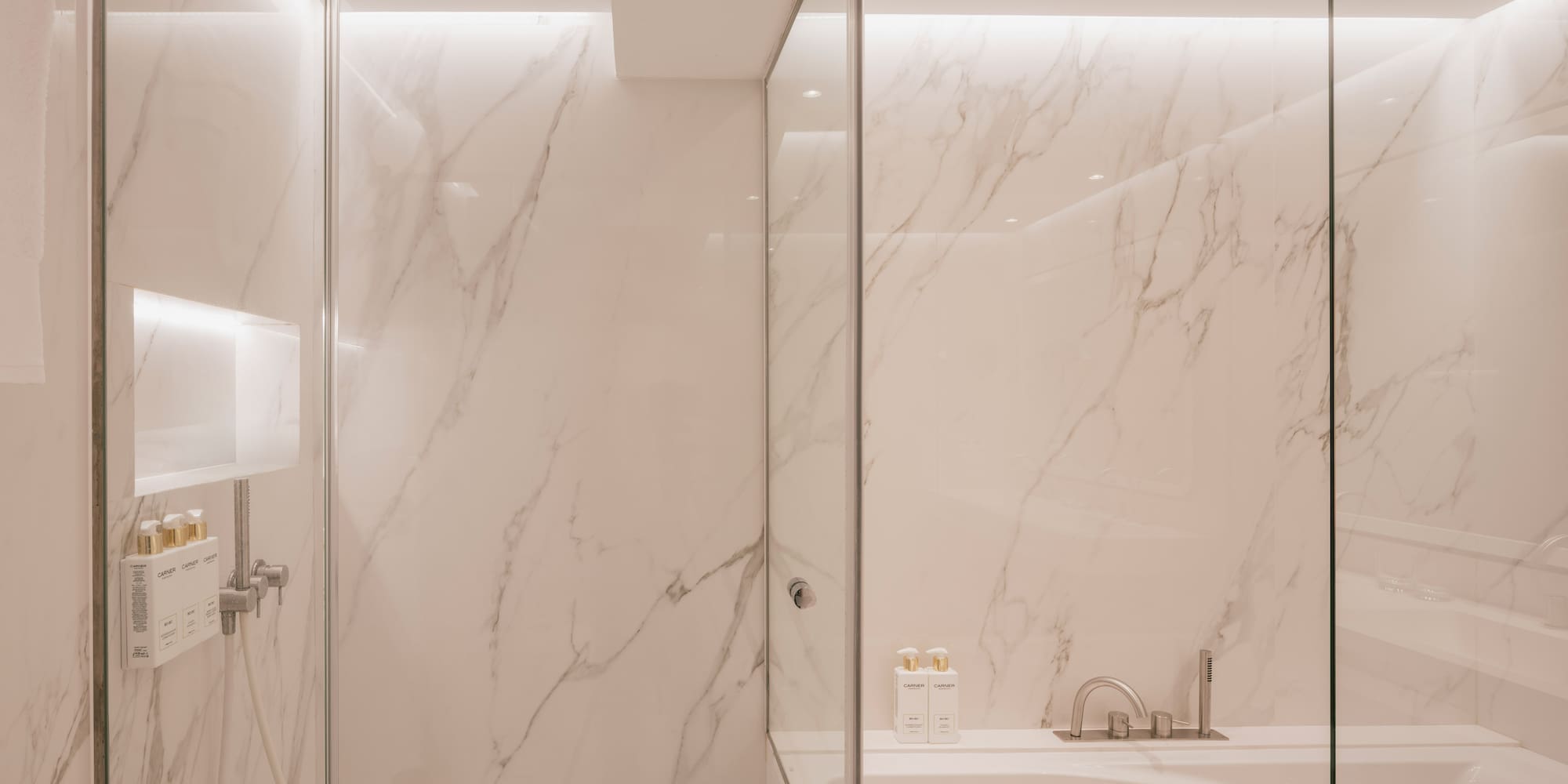 Modern marble bathroom with glass shower and tub.