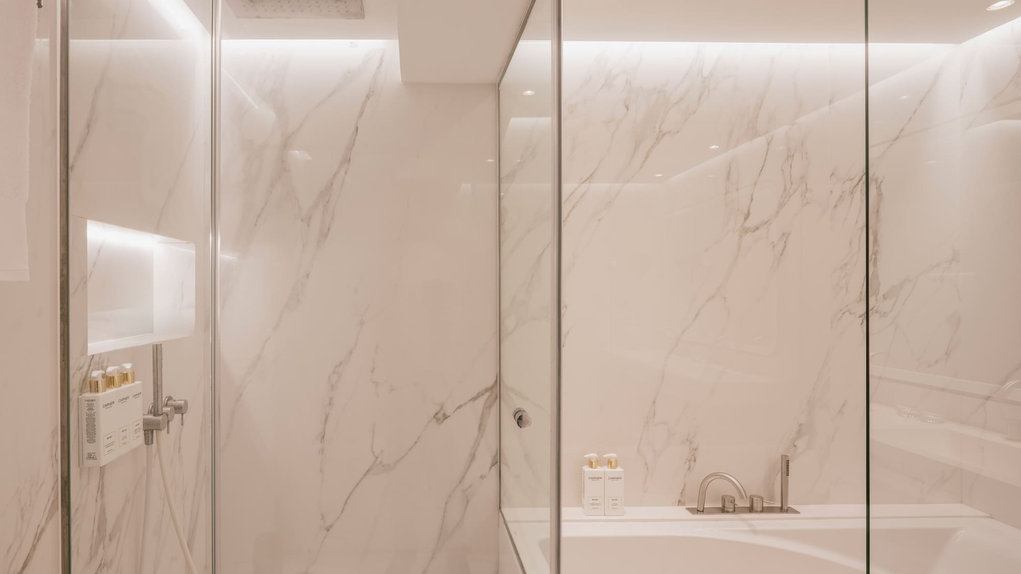 Modern marble bathroom with glass shower and tub.