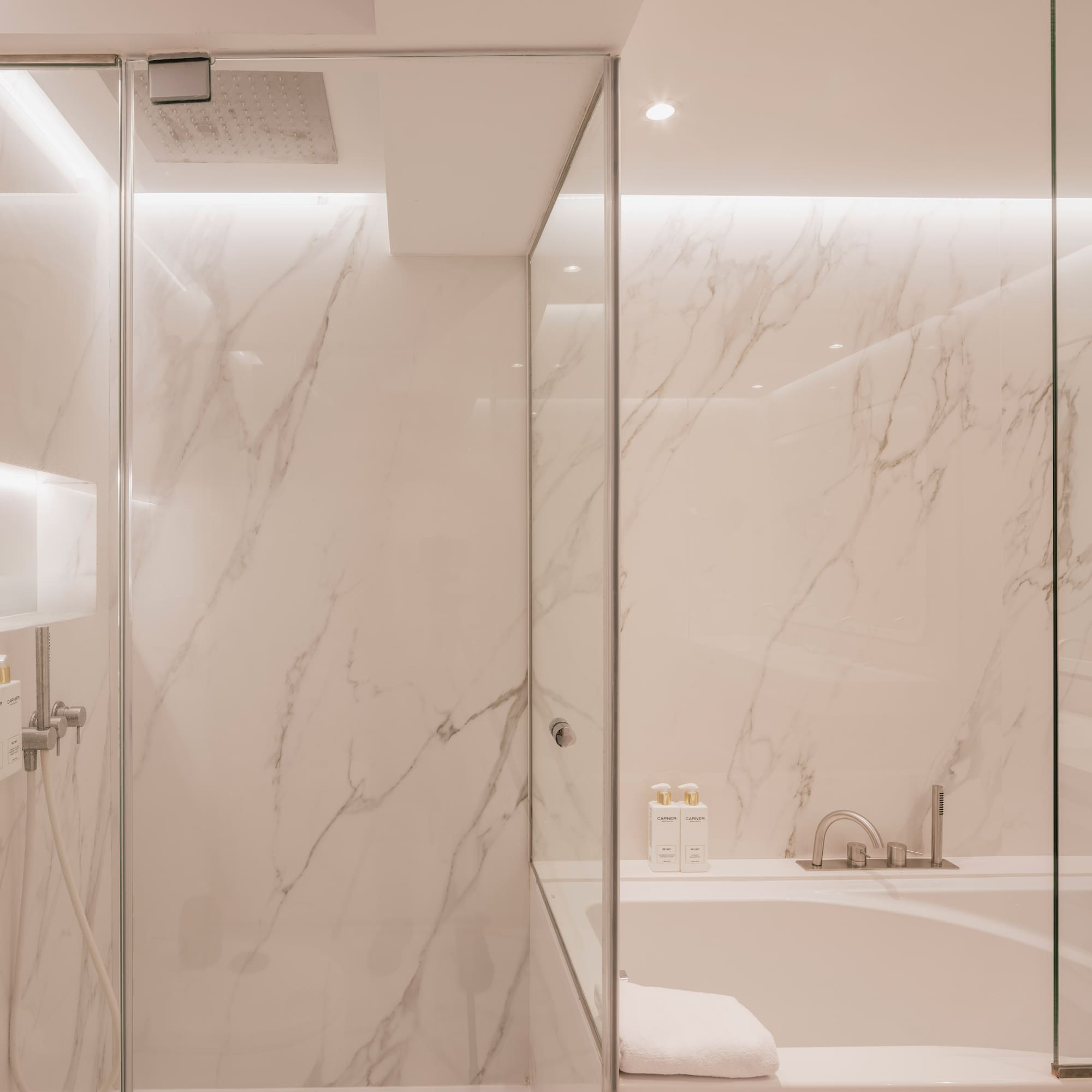 Modern marble bathroom with glass shower and tub.