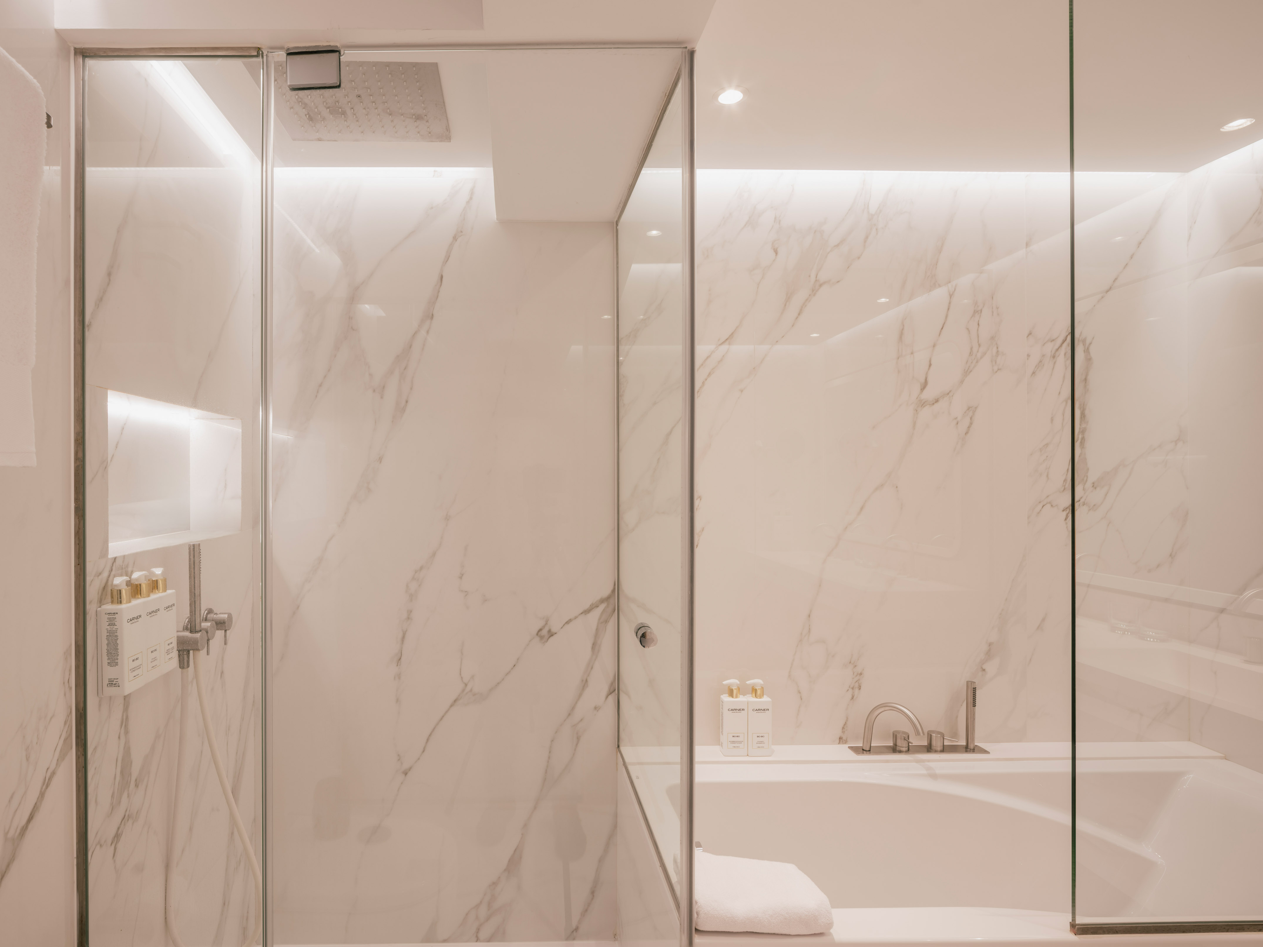 Modern marble bathroom with glass shower and tub.