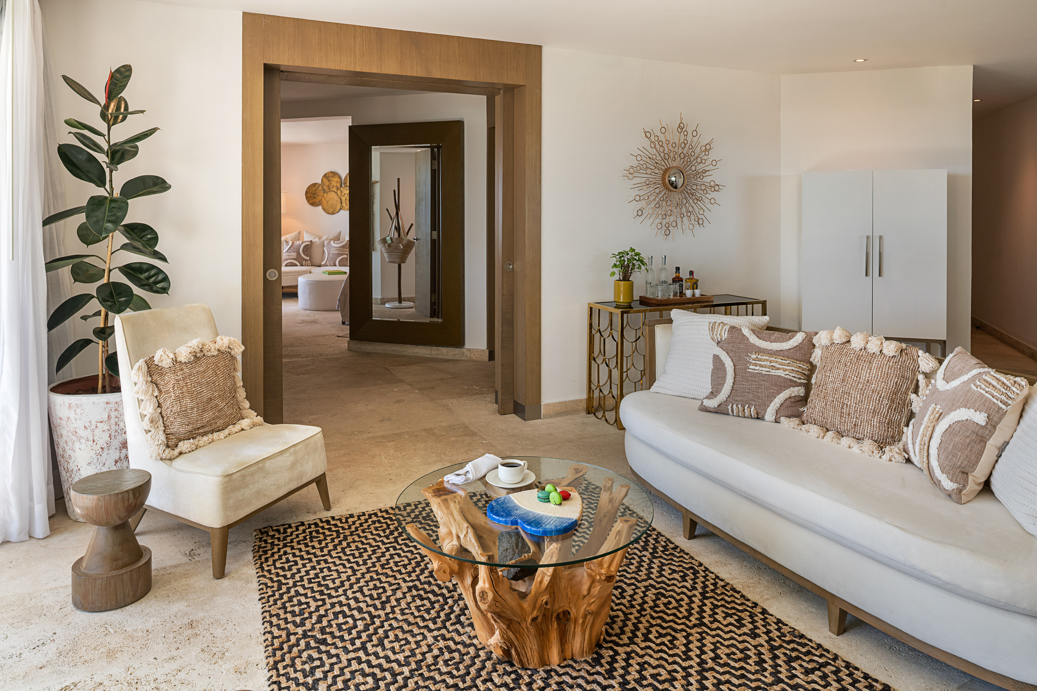 Stylish living room with white sofa, root coffee table, plant, and patterned rug.