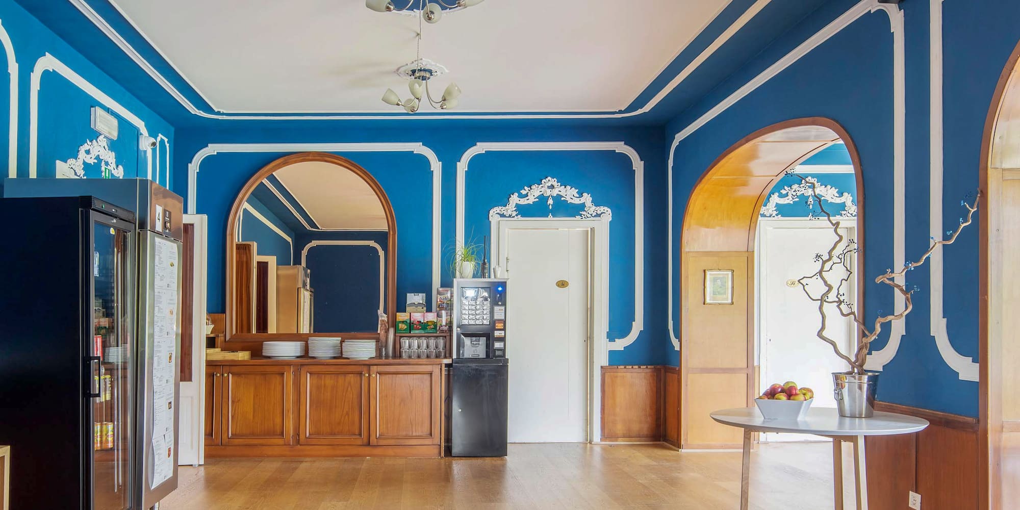 Royal blue breakfast room with ornate trim, wood floor, and coffee station.