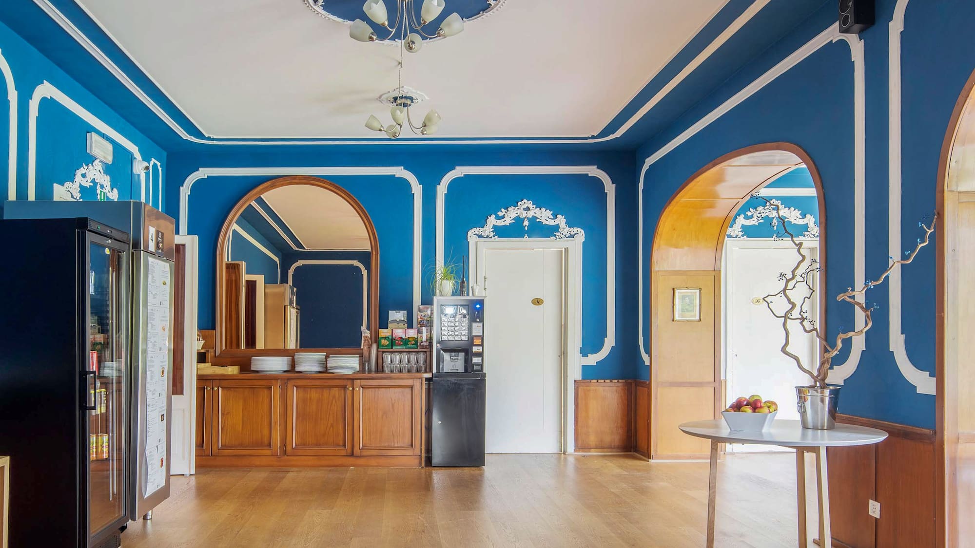 Royal blue breakfast room with ornate trim, wood floor, and coffee station.