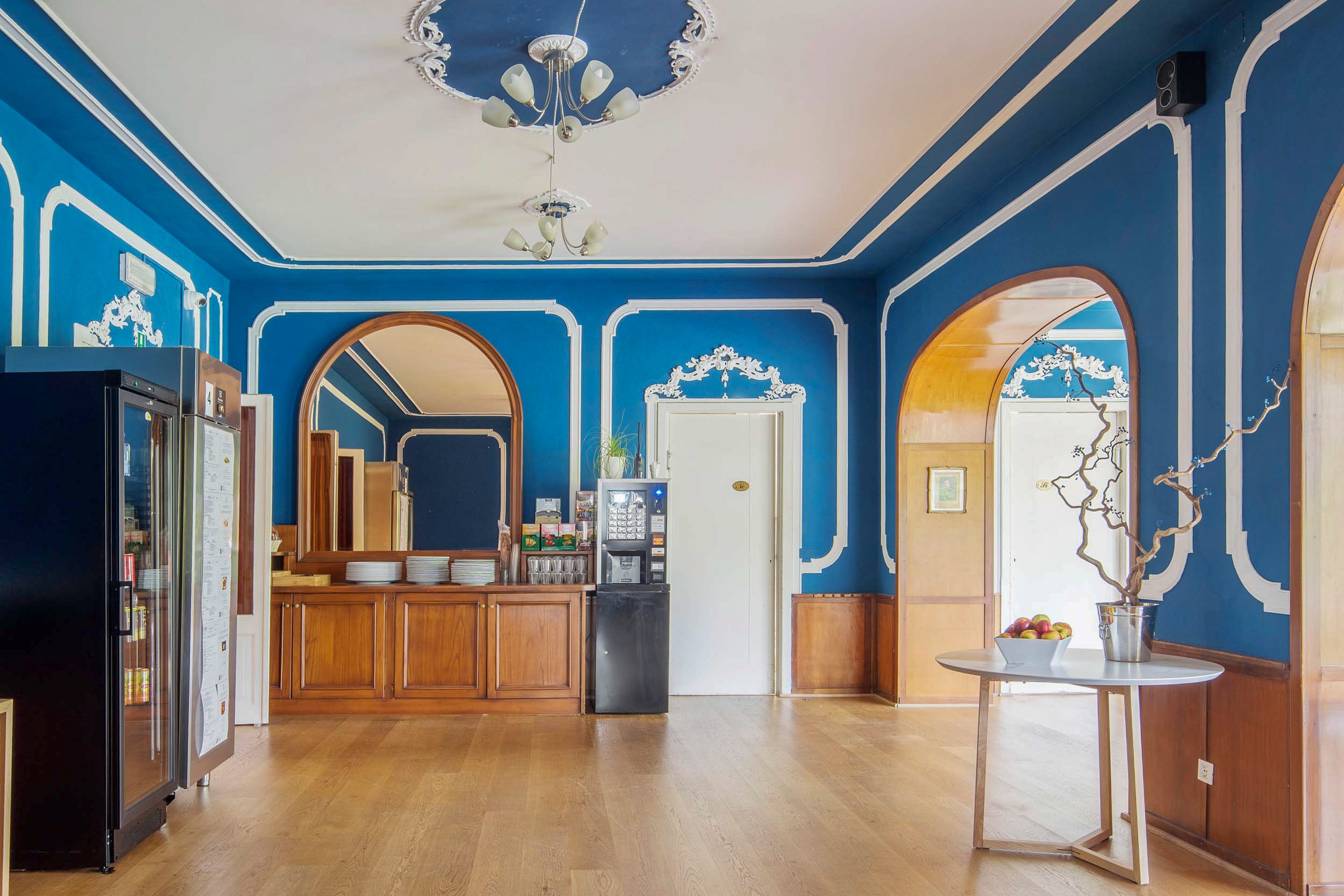 Royal blue breakfast room with ornate trim, wood floor, and coffee station.
