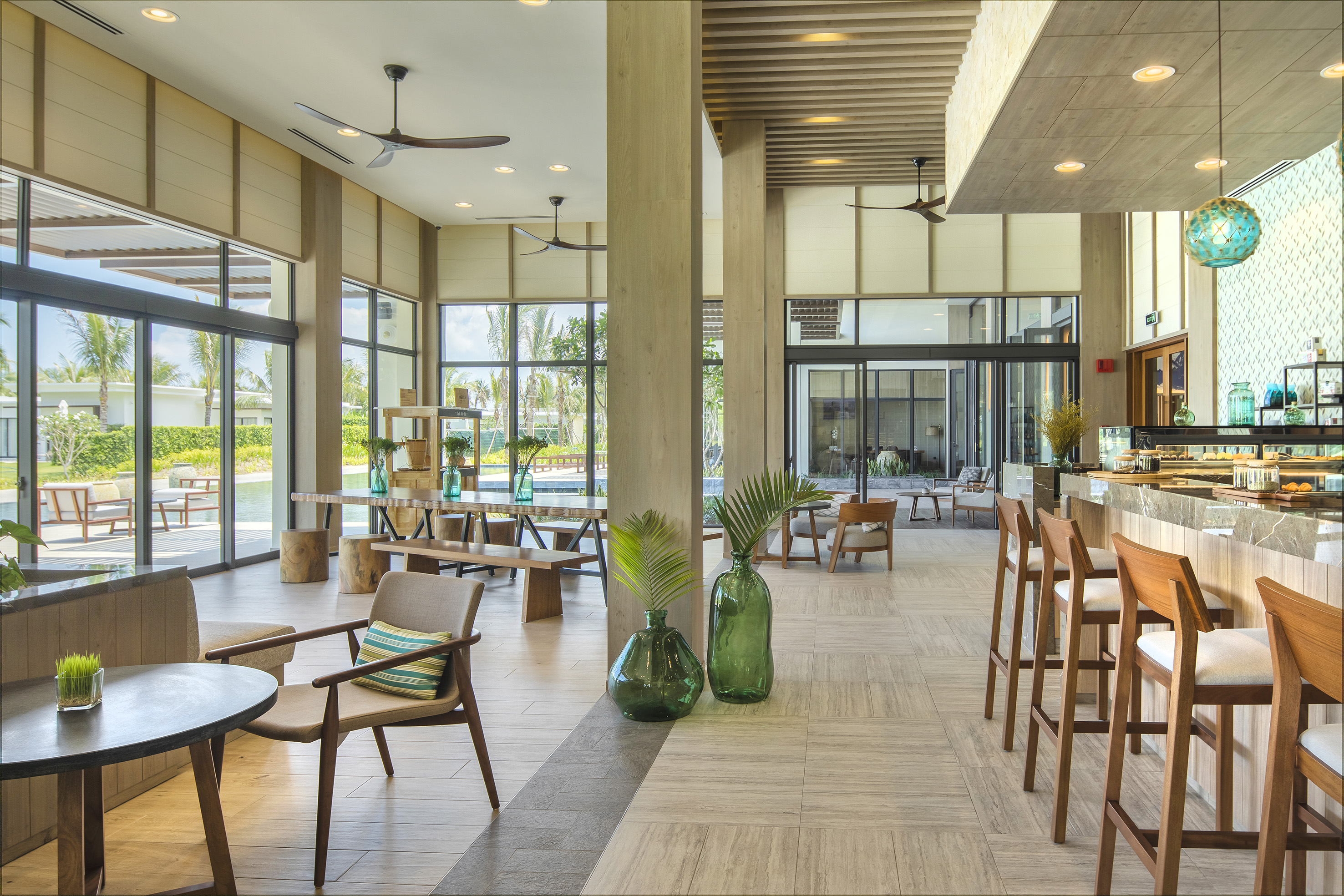 Resort lobby with bar, tropical view, and modern wood furnishings.