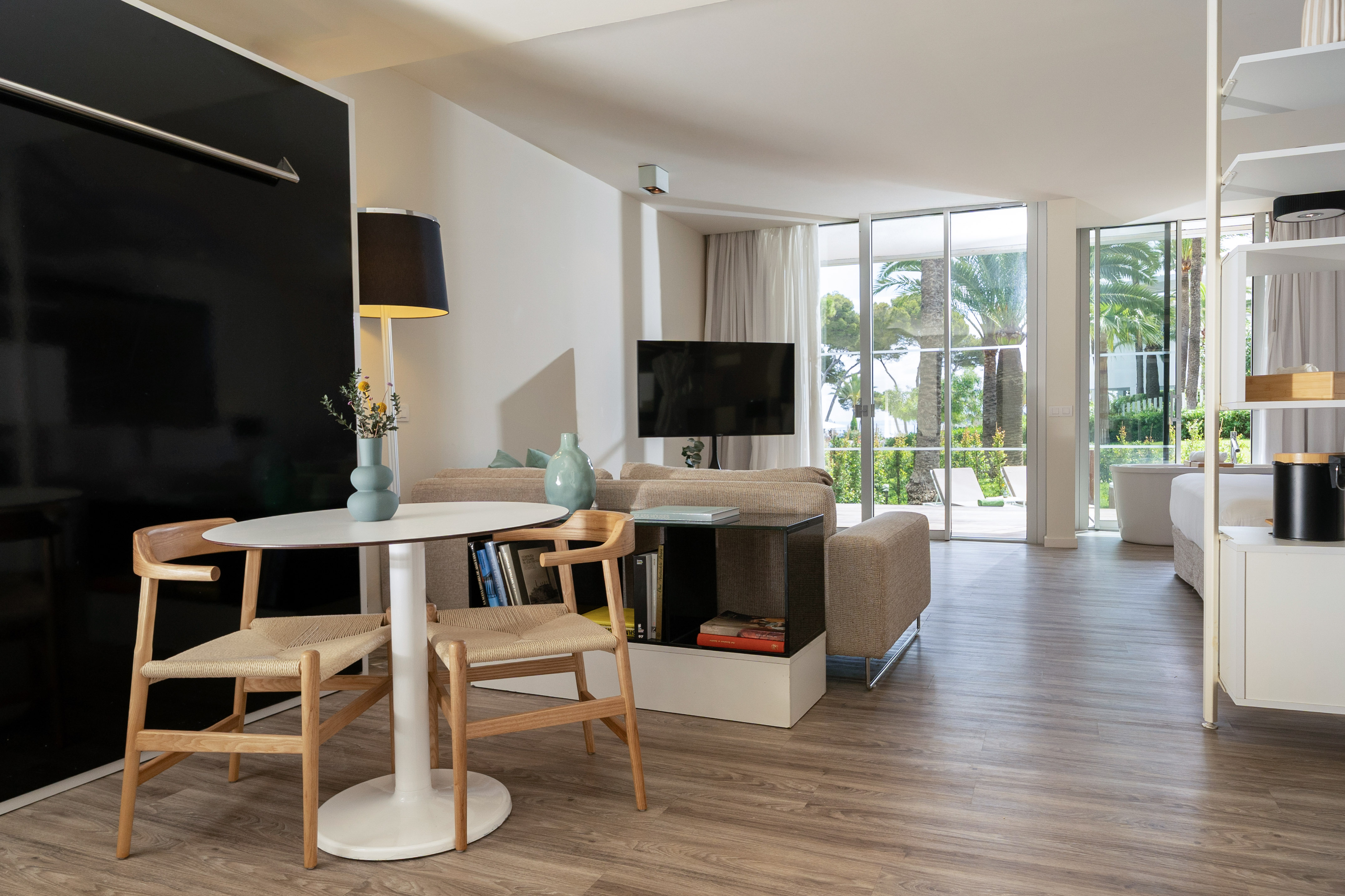 Modern suite living area with sofa, dining table, and tropical view.