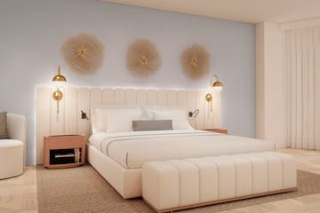 a bed with a white headboard and gold lights