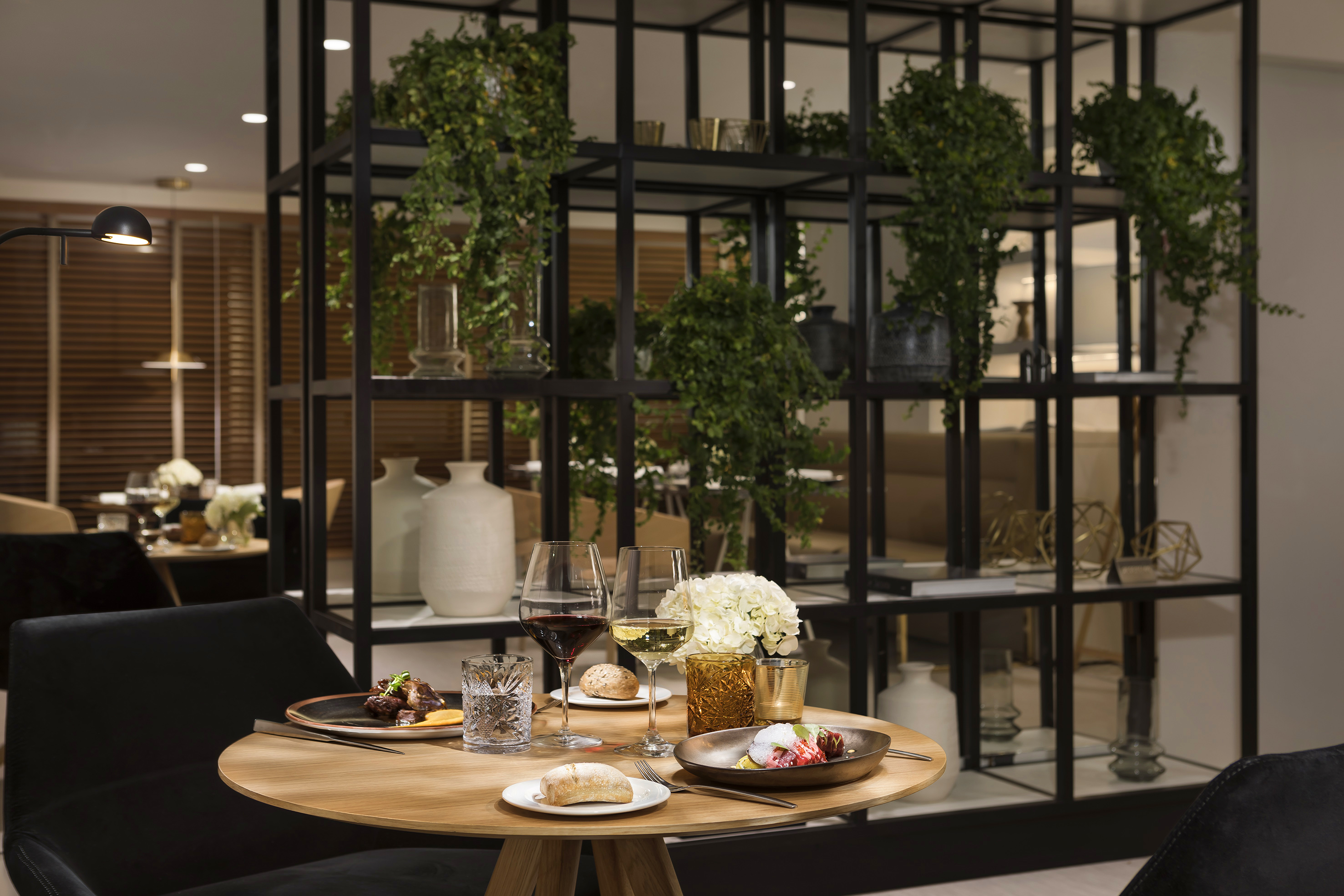 Elegant restaurant dining table with meal, wine, and modern green decor.